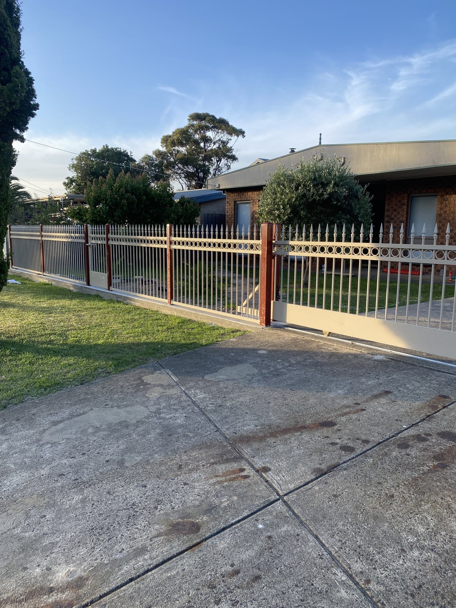 Cream metal palisade fence and gate along a driveway