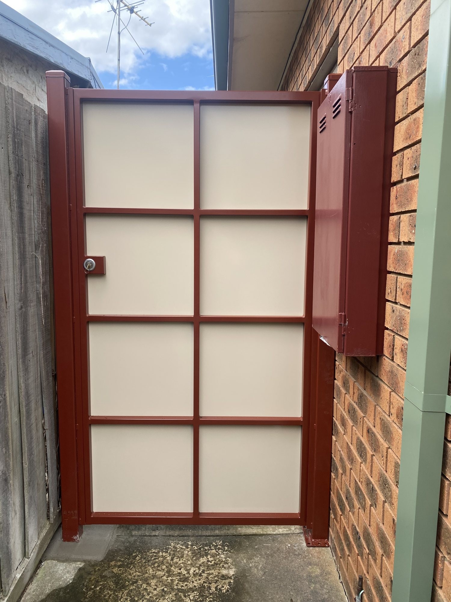Custom red-framed metal gate with cream grid panels