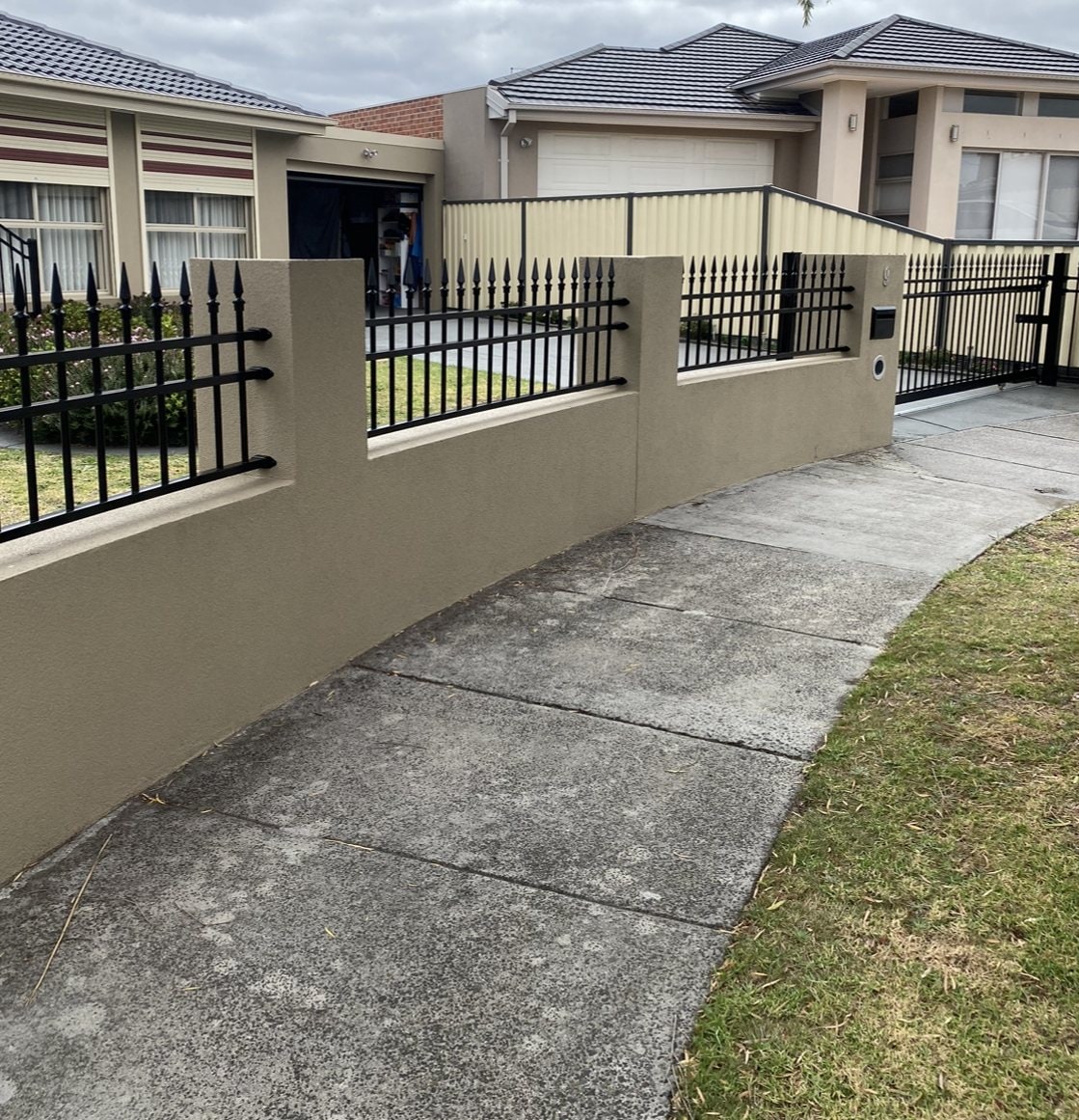 Black palisade fence on a cream rendered front wall