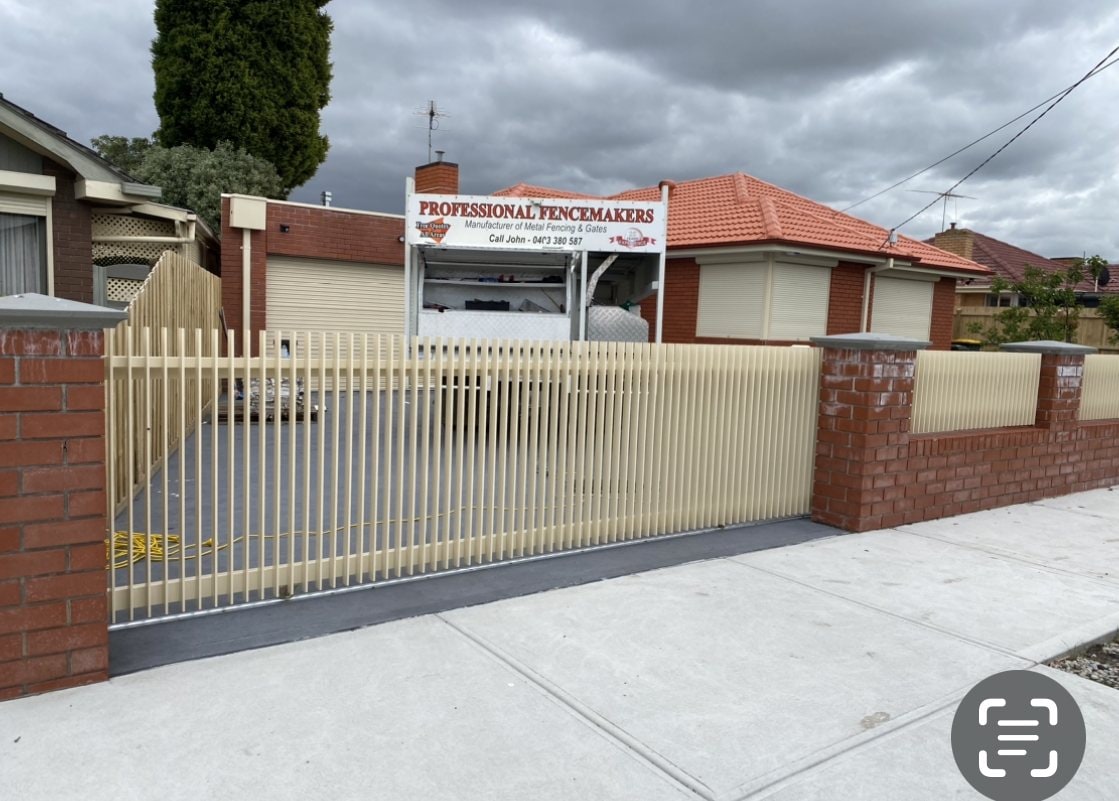 Cream palisade fence and gate with red brick piers