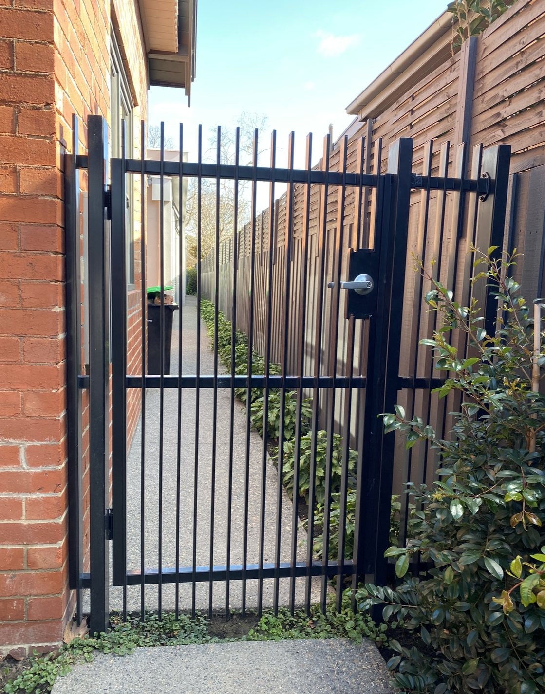 Black vertical bar pedestrian gate on a side path