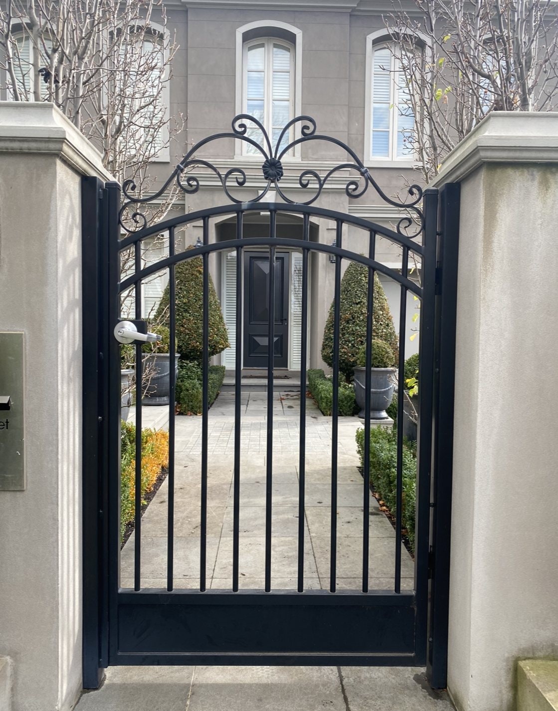 Arched black scrollwork pedestrian entry gate