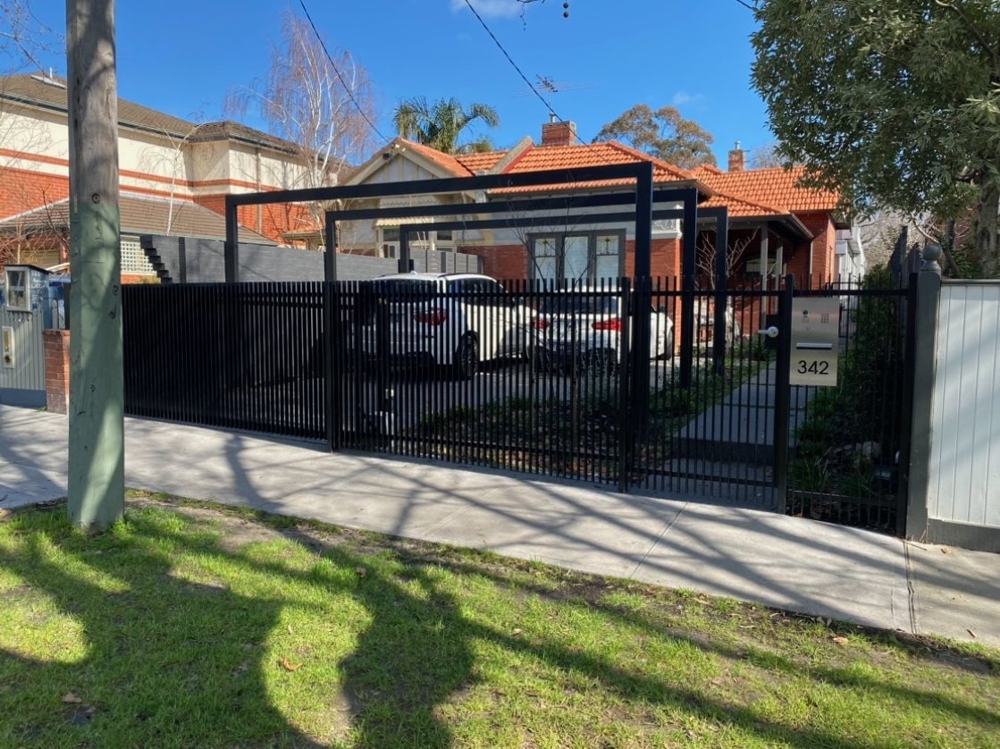 Black metal carport structure and palisade fence