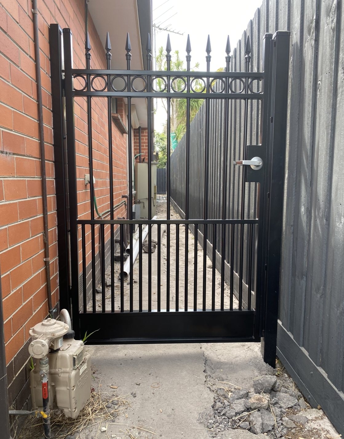 Black palisade pedestrian gate along a side path