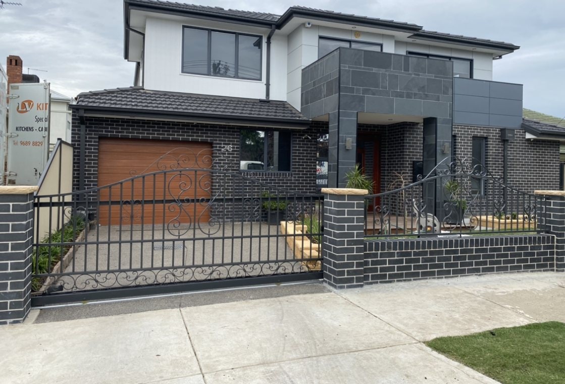Decorative black metal front fence and gate with brick piers