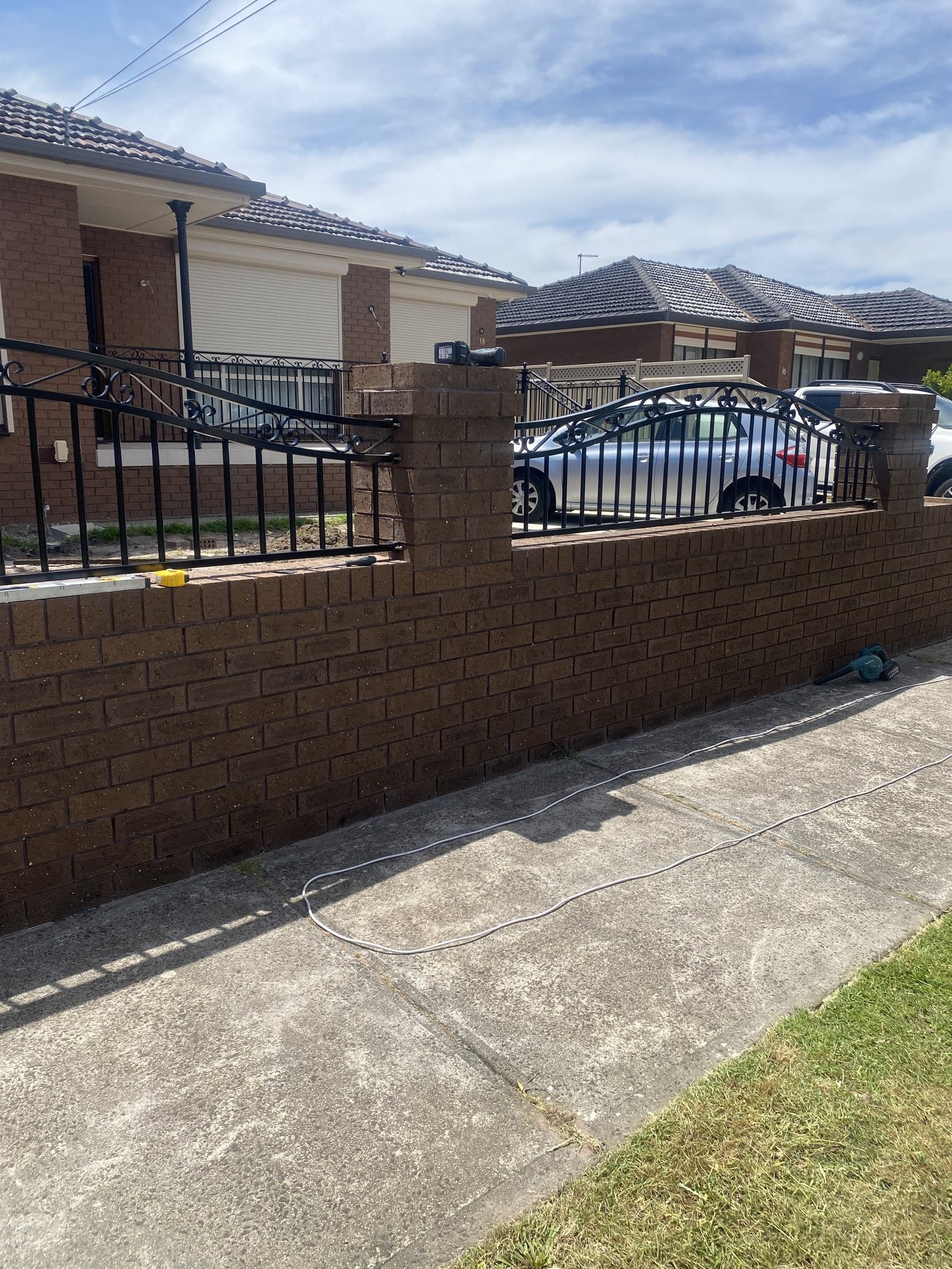Black ornamental metal infill on a brick pier front fence