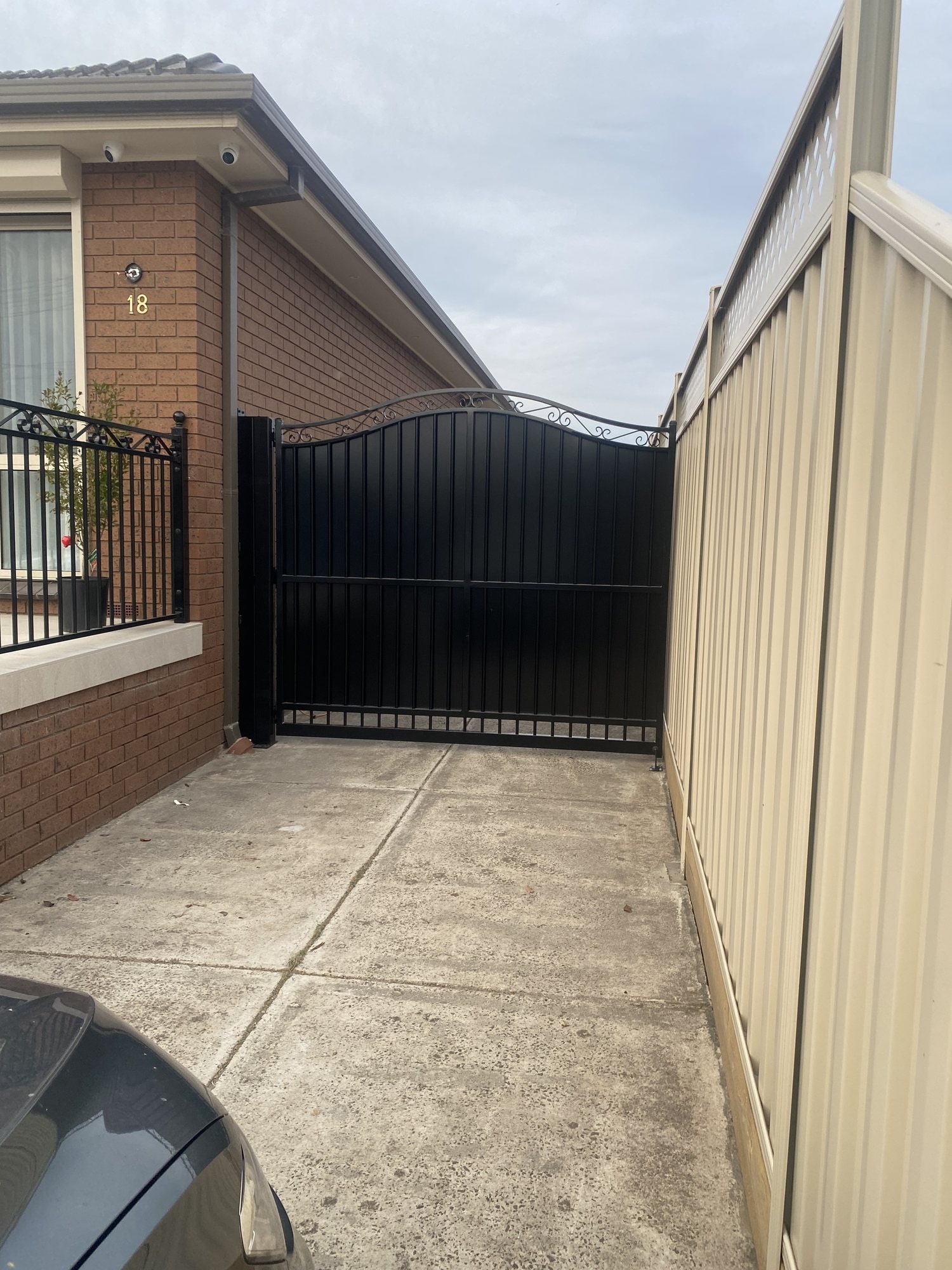 Arched black privacy gate beside a brick home