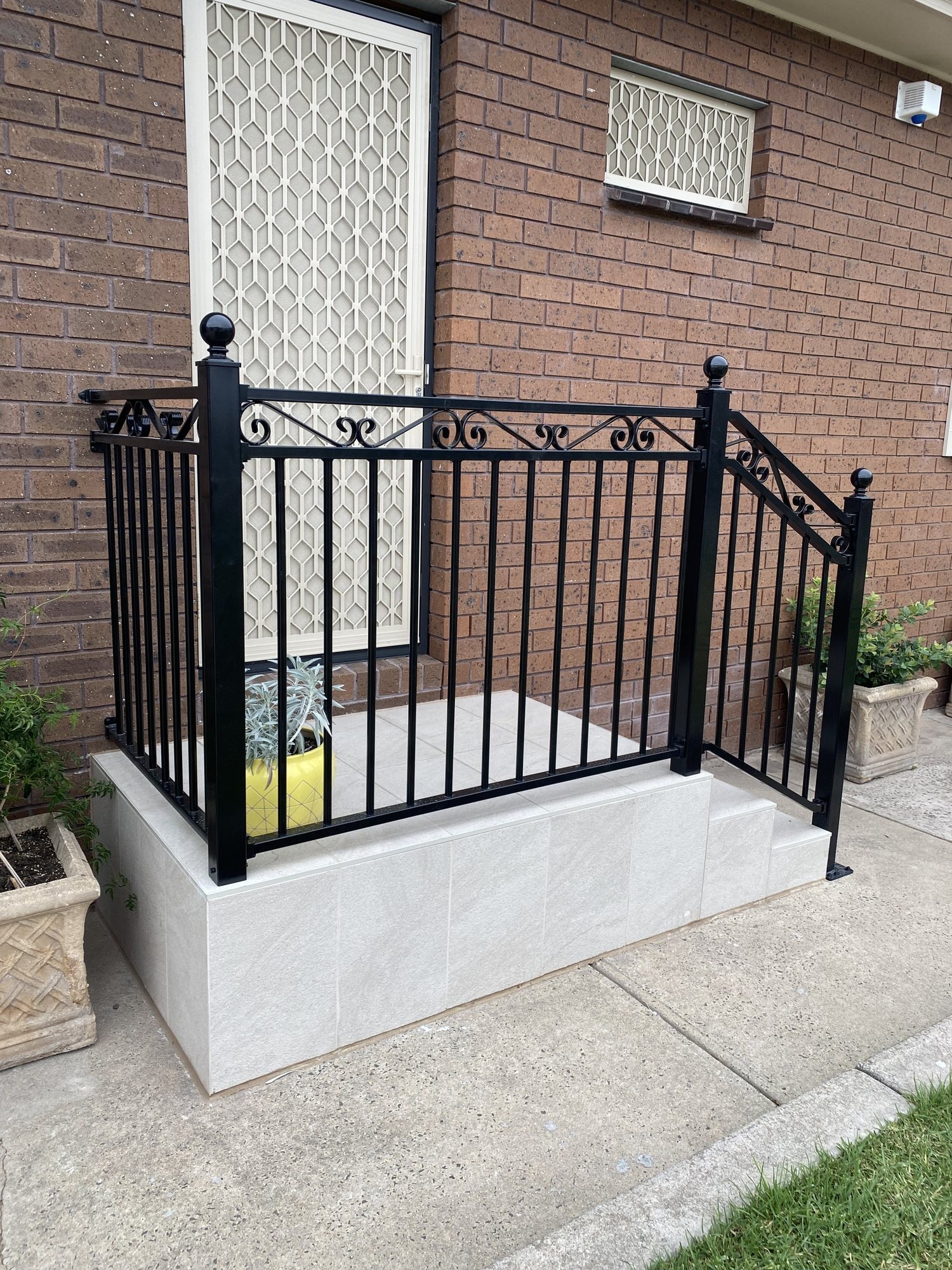 Black ornamental metal railing around a porch step