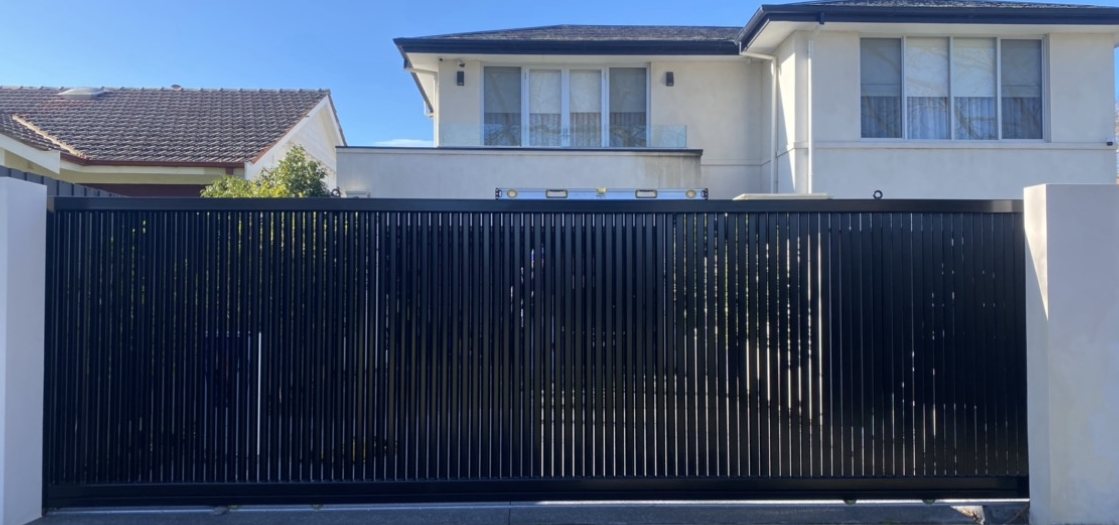 Black vertical slat driveway gate across a Melbourne home